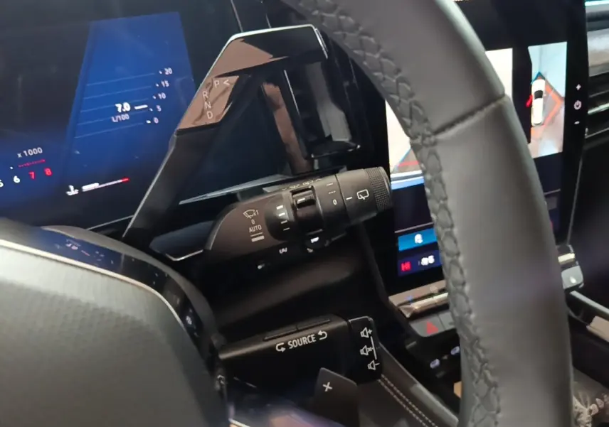 Gros plan intérieur sur le volant cuir noir et le combiné d'instruments numérique du Renault Austral bleu 2024.