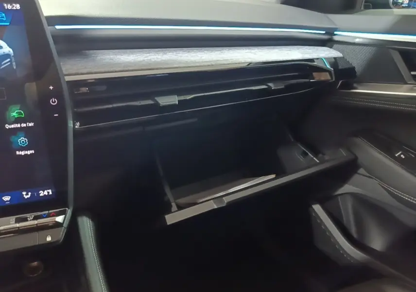 Intérieur du Renault Austral 2024, vue côté passager sur la boîte à gants ouverte et le tableau de bord noir avec inserts bois.