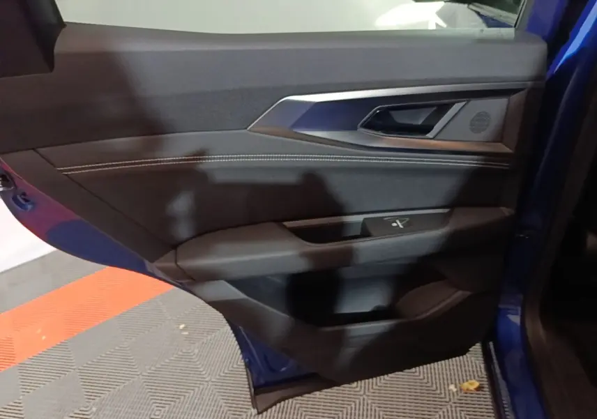 Vue rapprochée de la porte avant gauche bleu du Renault Austral 2024, montrant la poignée et les commandes de fenêtre.