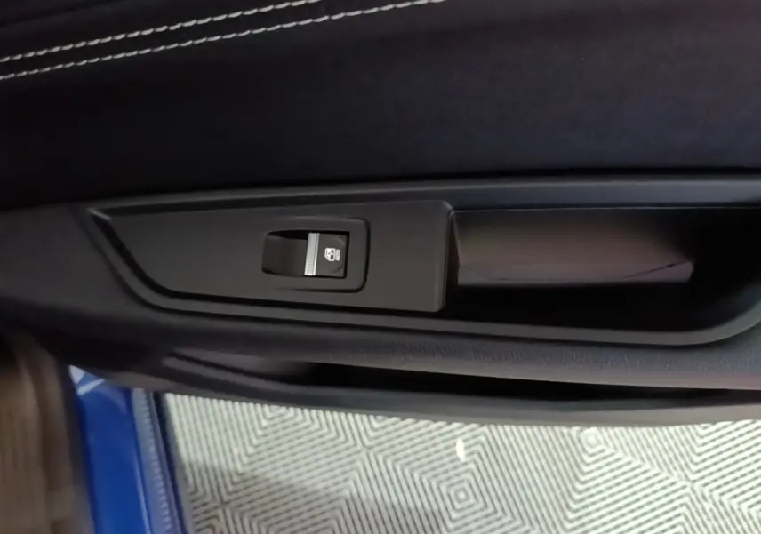 Détail de la commande de verrouillage électrique sur la porte intérieure côté gauche d’un Renault Austral bleu 2024.