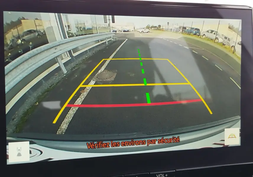 Vue caméra de recul du Toyota Corolla Cross gris acier 2025, avec lignes de guidage colorées et message de sécurité.
