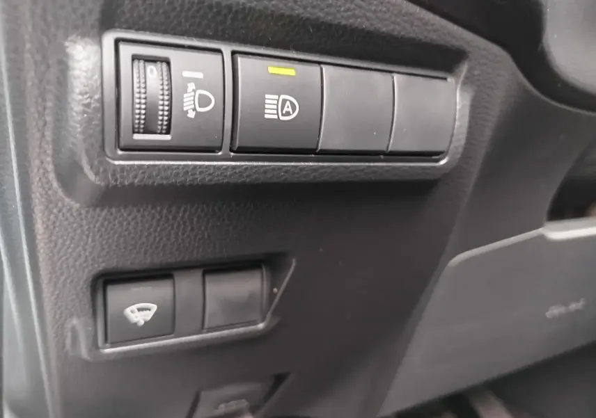 Gros plan sur les commandes d'éclairage et de désembuage côté gauche du tableau de bord noir du Toyota Corolla Cross 2025.