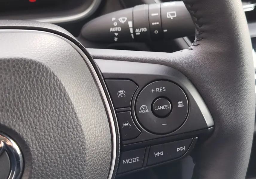 Détail du volant côté droit de la Toyota Corolla Cross gris acier 2025, avec commandes de régulateur et mode audio.