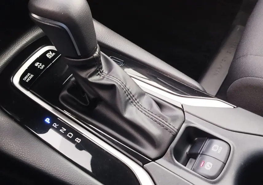 Gros plan sur la console centrale du Toyota Corolla Cross 2025, levier de vitesse automatique en cuir noir et commandes de mode de conduite.