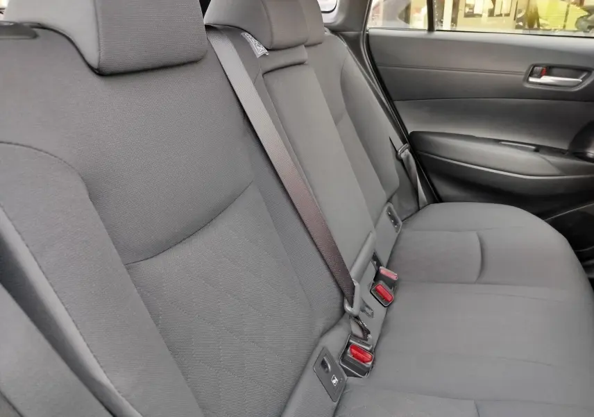 Vue du siège arrière côté droit de la Toyota Corolla Cross 2025 gris acier, avec ceinture de sécurité et tissu gris foncé.