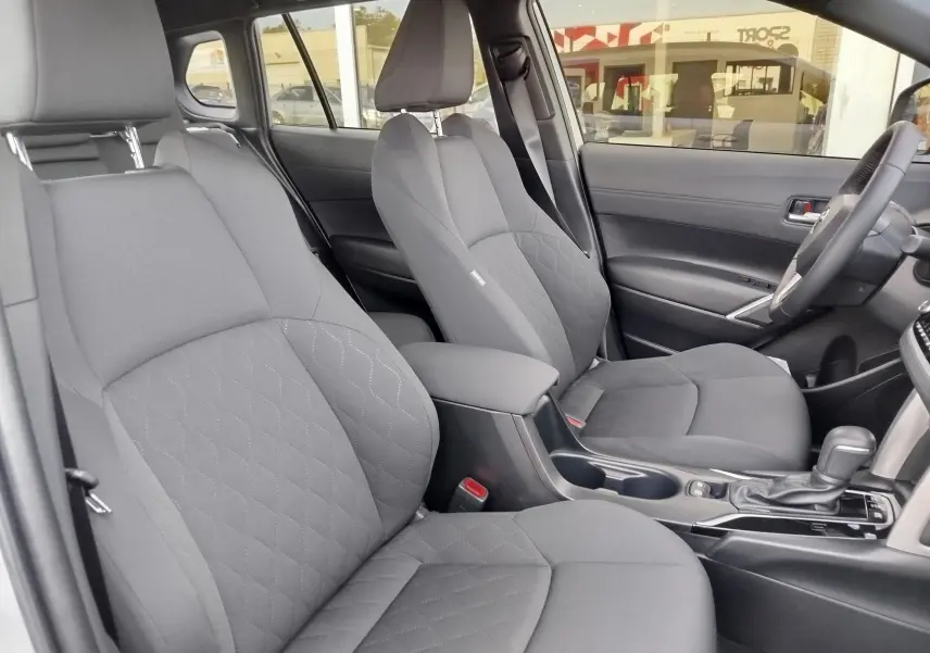 Vue intérieure côté droit montrant les sièges en tissu gris et la console centrale d'une Toyota Corolla Cross 2025 hybride.