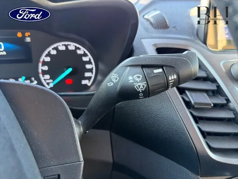 Gros plan sur la commande des essuie-glaces à gauche du volant dans l'habitacle du Ford Transit Connect blanc glacier.