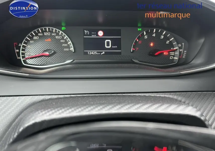 Tableau de bord de Peugeot 208 2024 avec compteur digital et compte-tours en vue frontale rapprochée.