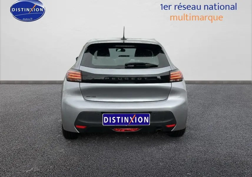 Vue arrière d'une Peugeot 208 1.2 PureTech 100 Active gris Artense avec feux arrière allumés sur fond neutre.