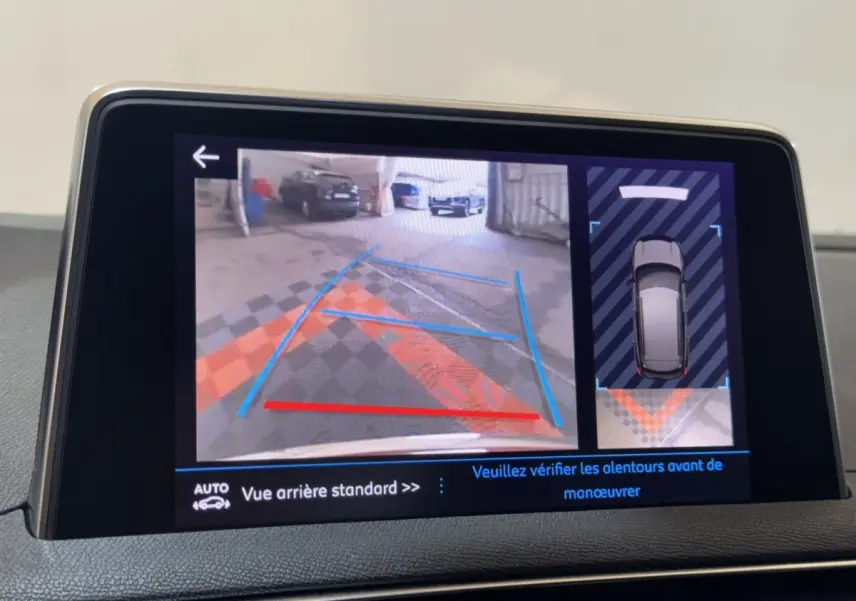 Écran tactile du système de navigation montrant la caméra de recul et l’aide au stationnement du Peugeot 3008 orange.