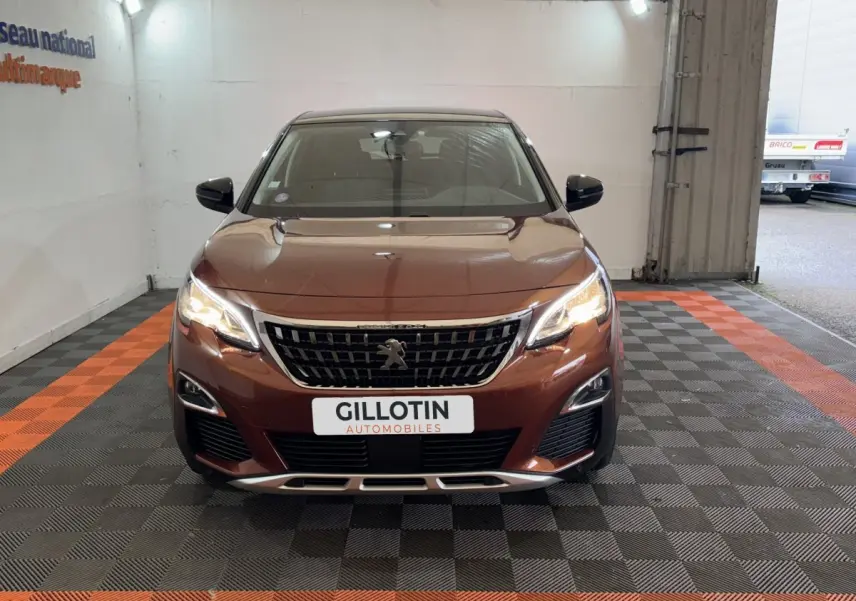 Vue de face d'un Peugeot 3008 orange 2020 avec calandre noire et phares LED allumés en intérieur.
