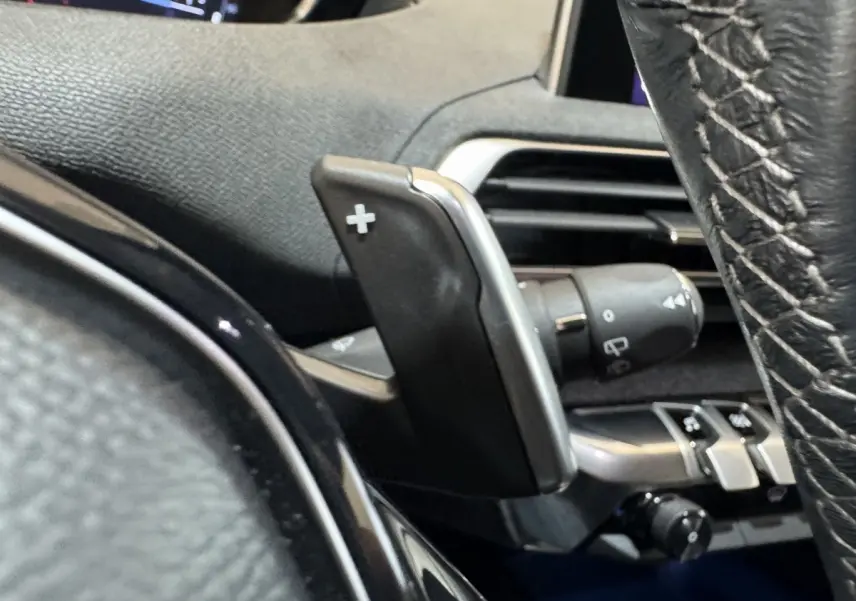 Gros plan sur la palette de changement de vitesses + au volant cuir noir du Peugeot 3008 orange, version PureTech 130.