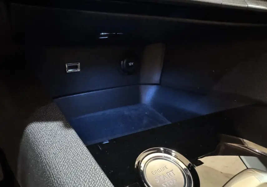Détail intérieur du Peugeot 3008 PureTech 130, bouton démarrage/arrêt moteur et prise 12V sur console noire.