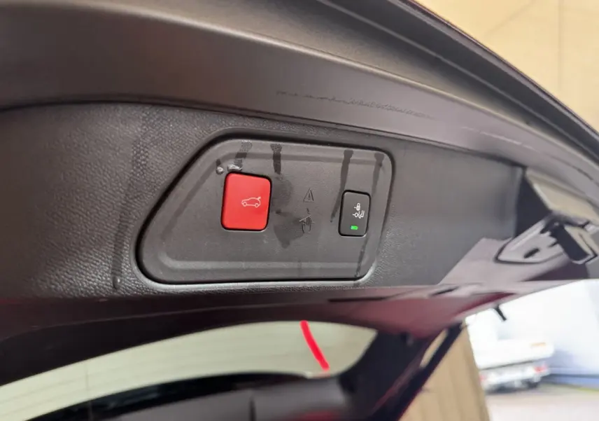 Gros plan sur les boutons d'ouverture et fermeture électrique du coffre du Peugeot 3008 orange, vue intérieure arrière.