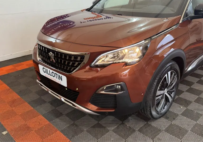 Vue 3/4 avant droit d'un Peugeot 3008 orange avec calandre noire et jantes alliage, phare allumé en intérieur showroom.