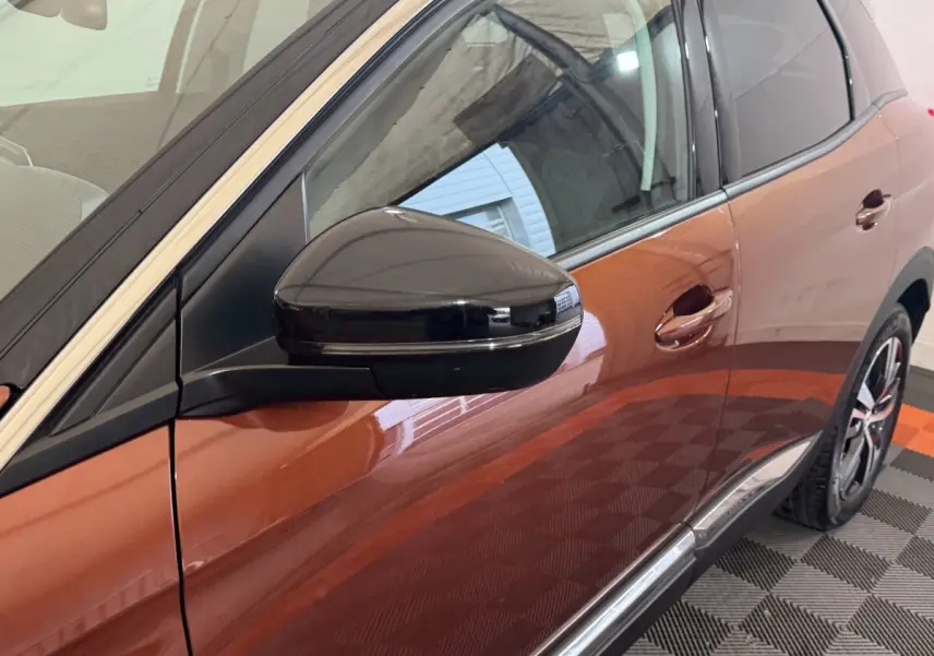 Vue latérale droite rapprochée du Peugeot 3008 orange, mettant en valeur le rétroviseur noir brillant et la poignée de porte.