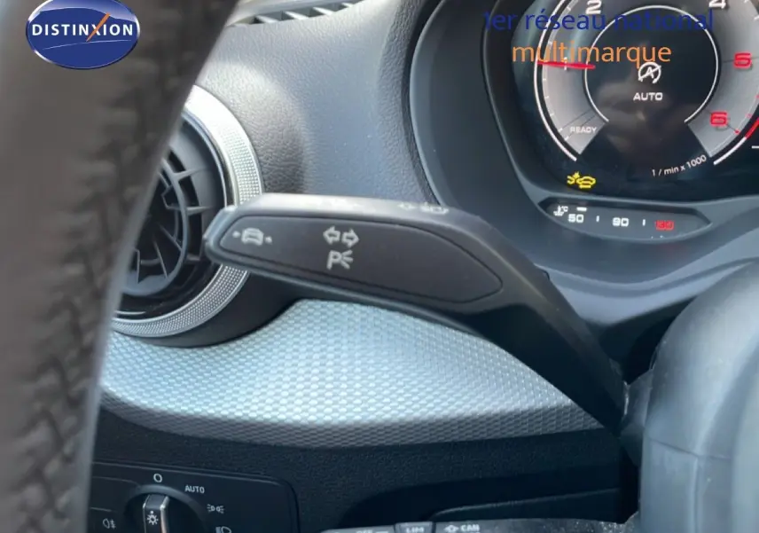Gros plan sur le combiné d'instruments et la commande de clignotants d'un Audi Q2 gris Manhattan, intérieur noir.