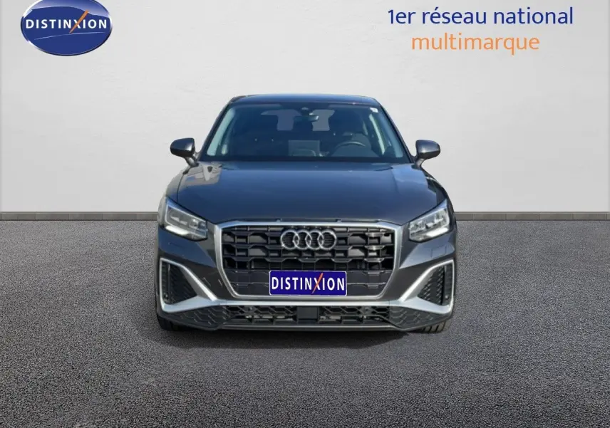 Vue frontale d'un Audi Q2 30 TDI S-Line gris Manhattan métallisé avec calandre noire et phares LED allumés.
