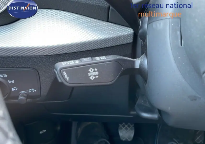 Gros plan sur la commande de régulateur de vitesse à gauche du volant dans l’Audi Q2 gris Manhattan 2025.