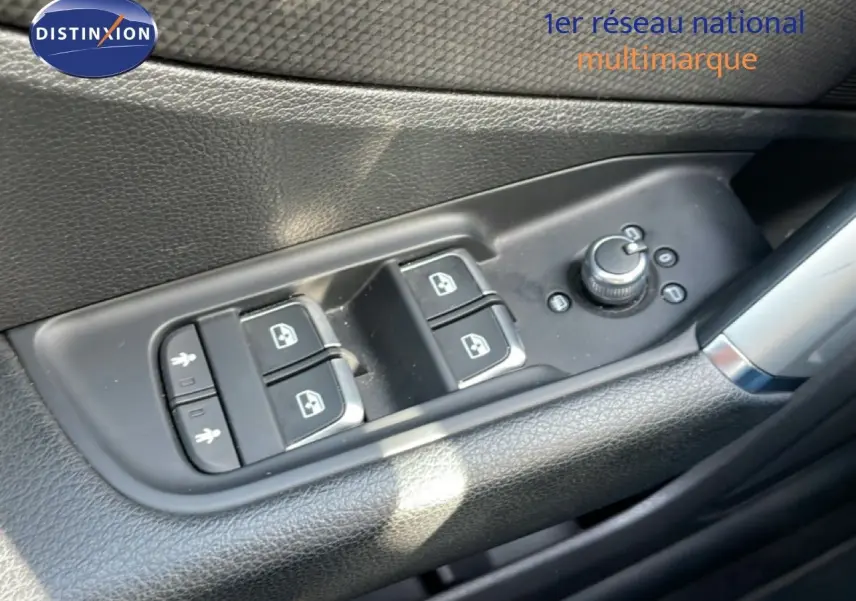 Gros plan sur les commandes de lève-vitres et rétroviseurs côté conducteur de l'Audi Q2 gris Manhattan 2025.