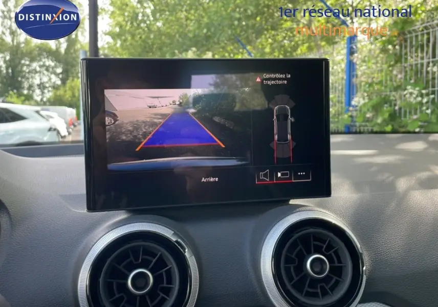 Écran central de l’Audi Q2 30 TDI S-Line 2025 montrant la caméra de recul avec guidage de trajectoire, intérieur gris.