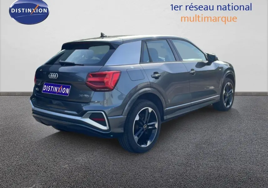 Audi Q2 30 TDI S-Line gris Manhattan métal, vue 3/4 arrière droit, jantes noires et feux arrière LED visibles.