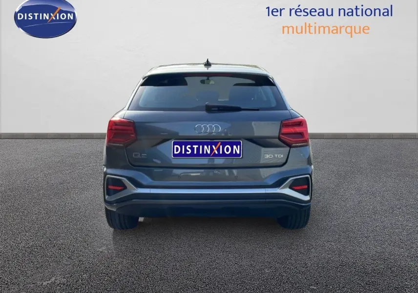 Vue arrière d'un Audi Q2 30 TDI S-Line gris Manhattan métal, mettant en valeur ses feux et son logo distinctifs.