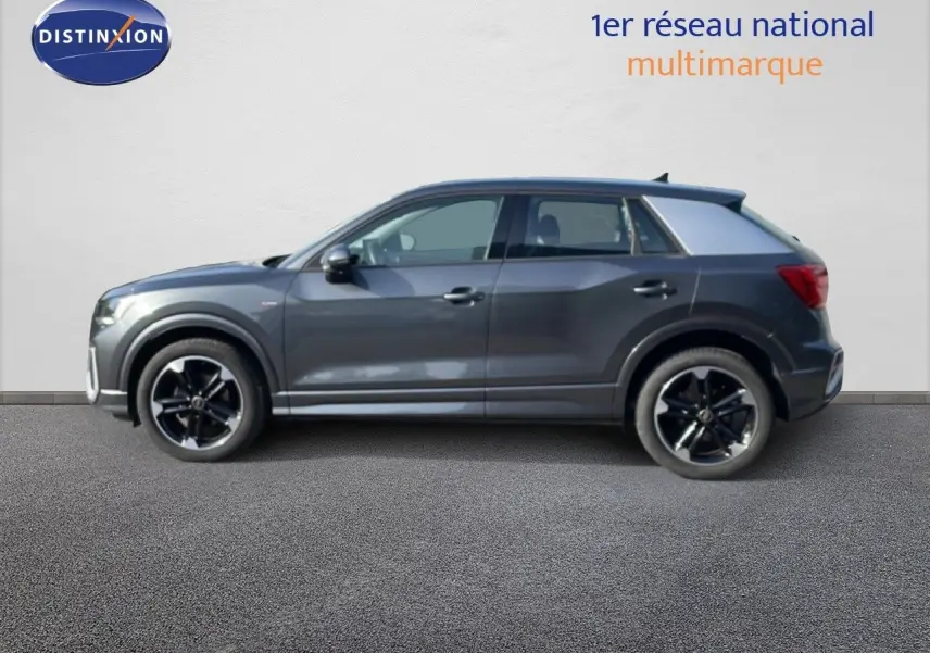 Audi Q2 30 TDI S-Line gris Manhattan vu de profil côté gauche, avec jantes noires et détails sportifs visibles.