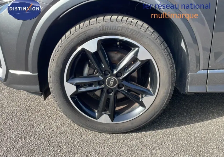 Gros plan sur la roue avant droite d’un Audi Q2 gris Manhattan avec jante alliage bicolore et pneu Bridgestone.