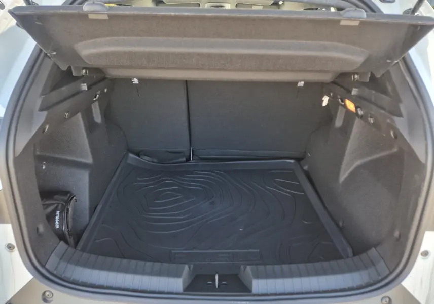 Coffre ouvert vu de l'arrière d'un Dacia Duster blanc 2026, avec tapis de protection noir et intérieur spacieux.