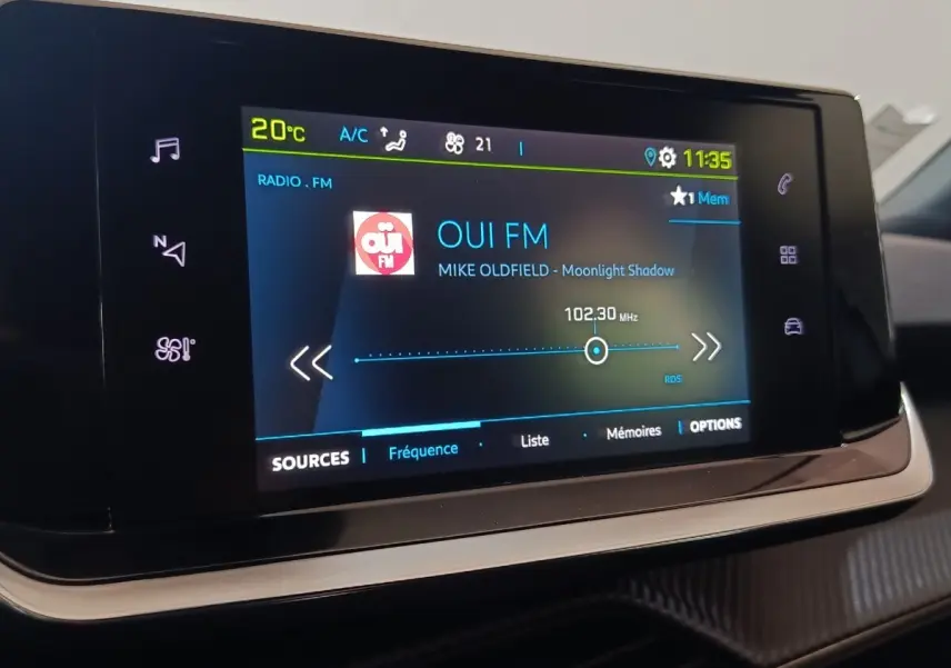 Écran tactile central du tableau de bord de la Peugeot E-2008 électrique, affichant la radio FM.