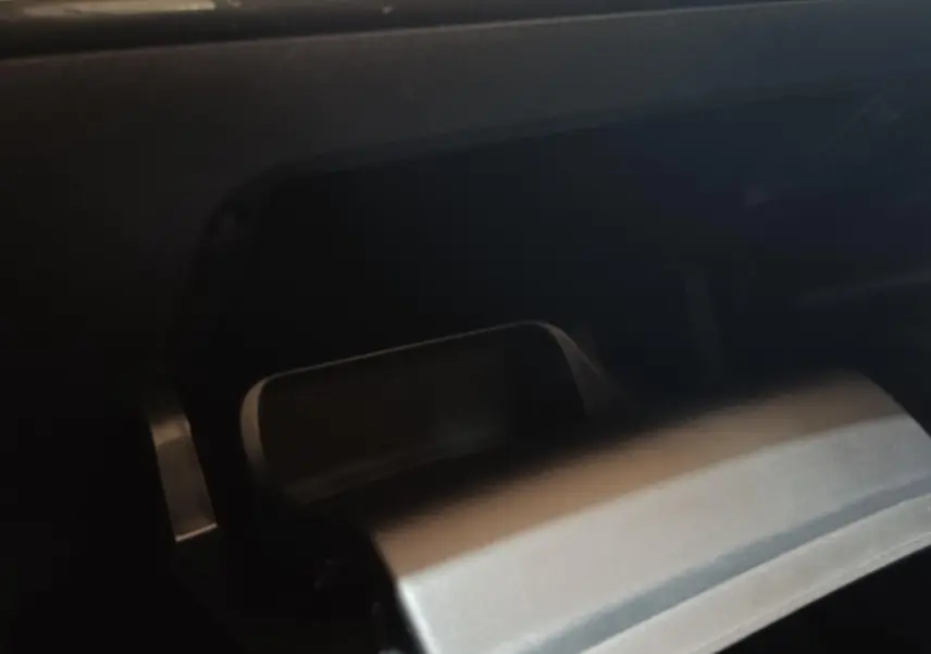 Gros plan sur la boîte à gants réfrigérée ouverte du Peugeot E-2008 électrique gris clair, intérieur sombre.