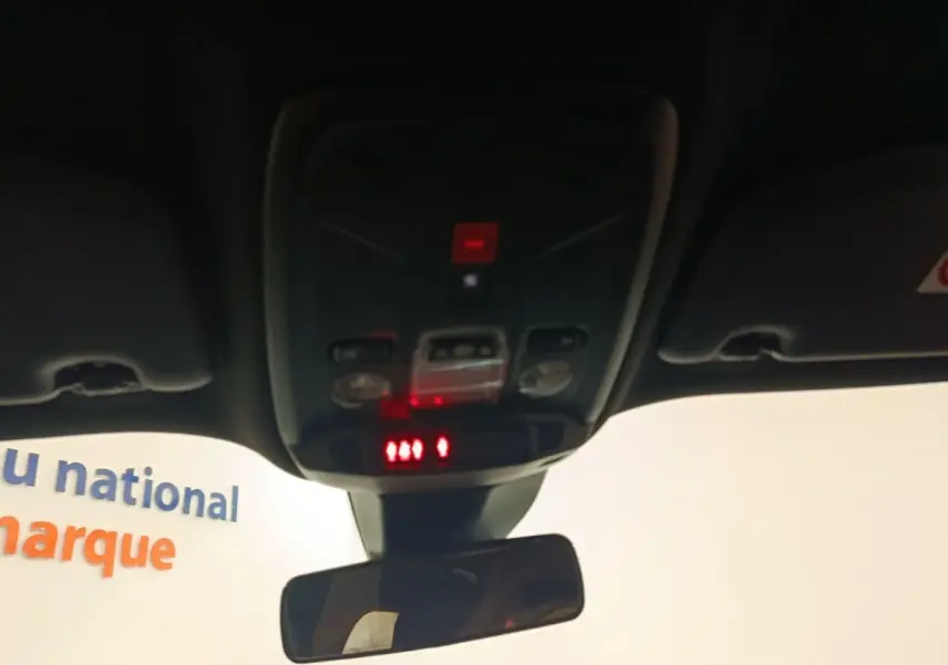 Vue intérieure du plafond avant de la Peugeot E-2008 électrique 2023, avec éclairage et commandes au-dessus du rétroviseur central.