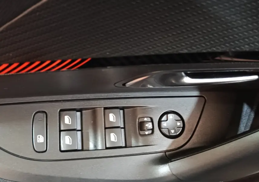 Gros plan sur les commandes des vitres électriques et rétroviseurs côté conducteur du Peugeot E-2008 électrique gris clair 2023.