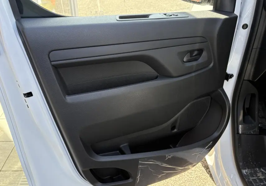 Vue de la porte avant droite ouverte d'un Opel Vivaro blanc, montrant le panneau intérieur noir avec rangement intégré.