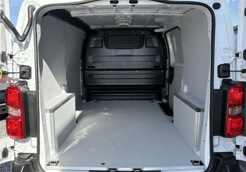 Vue arrière du fourgon blanc Opel Vivaro 2024, montrant l'espace de chargement avec plancher et habillages latéraux en bois.