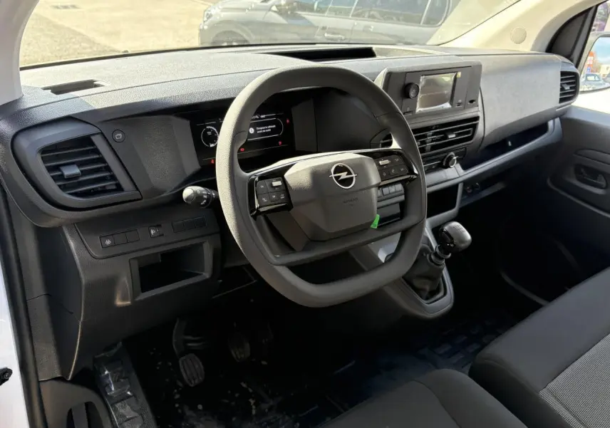 Intérieur du poste de conduite Opel Vivaro blanc 2024, vue côté conducteur sur volant multifonction et tableau de bord numérique.