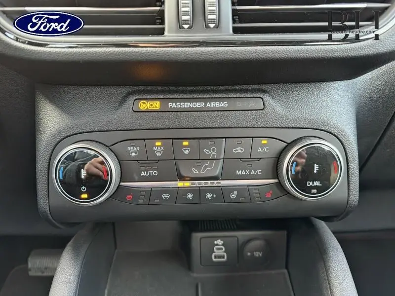 Vue rapprochée de la console de climatisation du Ford Kuga gris, avec commandes tactiles et affichages lumineux.