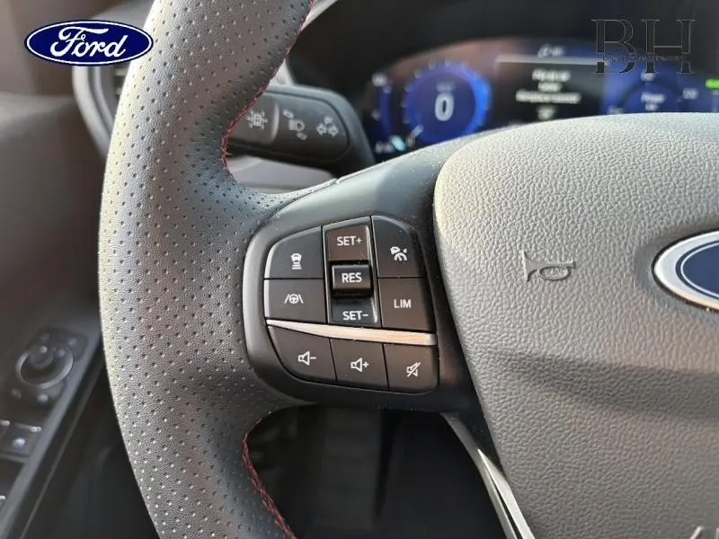 Gros plan sur le volant cuir perforé avec commandes multifonctions du Ford Kuga gris Magnetic Métallisé 2023.