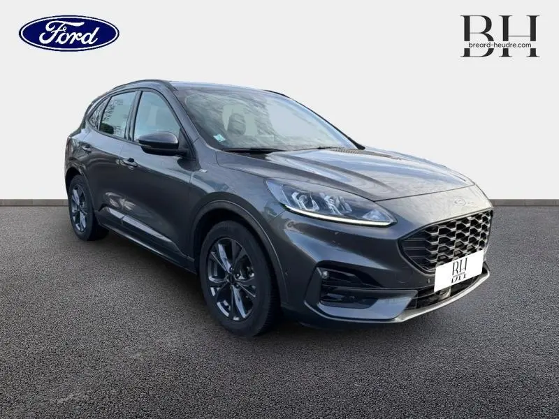 Vue 3/4 avant droit d'un Ford Kuga 2023 gris Magnetic métallisé avec calandre noire et jantes alliage.