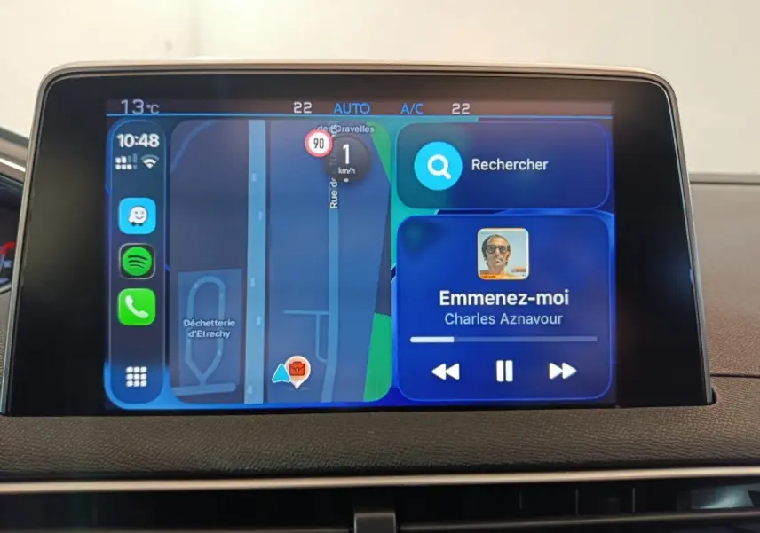 Écran tactile central du tableau de bord du Peugeot 3008 blanc, affichant navigation et musique en cours.
