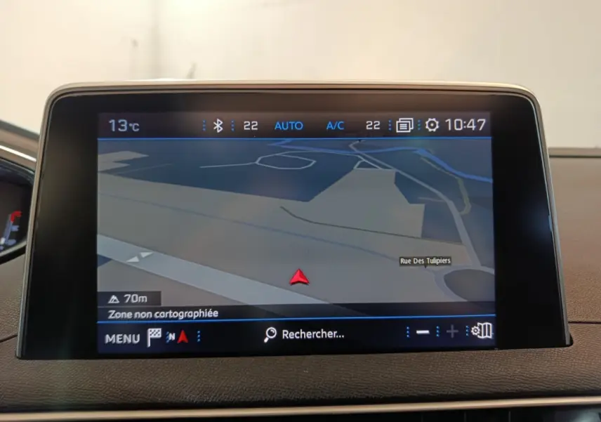 Écran tactile central du tableau de bord du Peugeot 3008 blanc, affichant la navigation GPS en mode 3D.