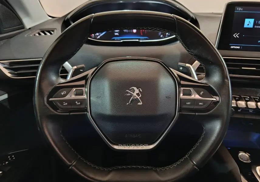 Vue rapprochée du volant cuir noir du Peugeot 3008 2019 avec commandes multifonctions et tableau de bord digital.