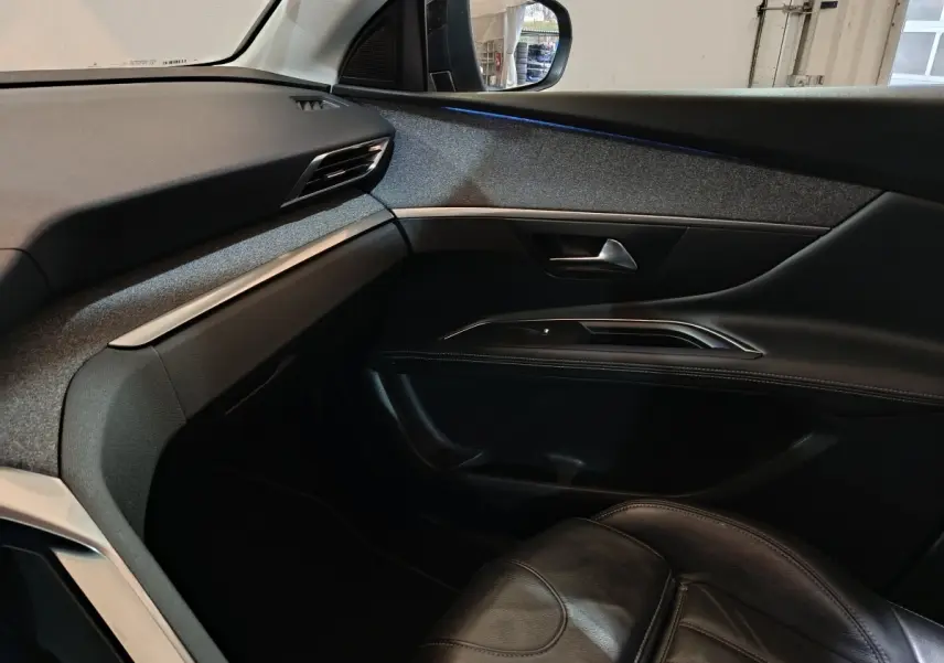 Vue intérieure côté passager du Peugeot 3008 blanc, montrant la portière et le tableau de bord avec finitions noires et grises.