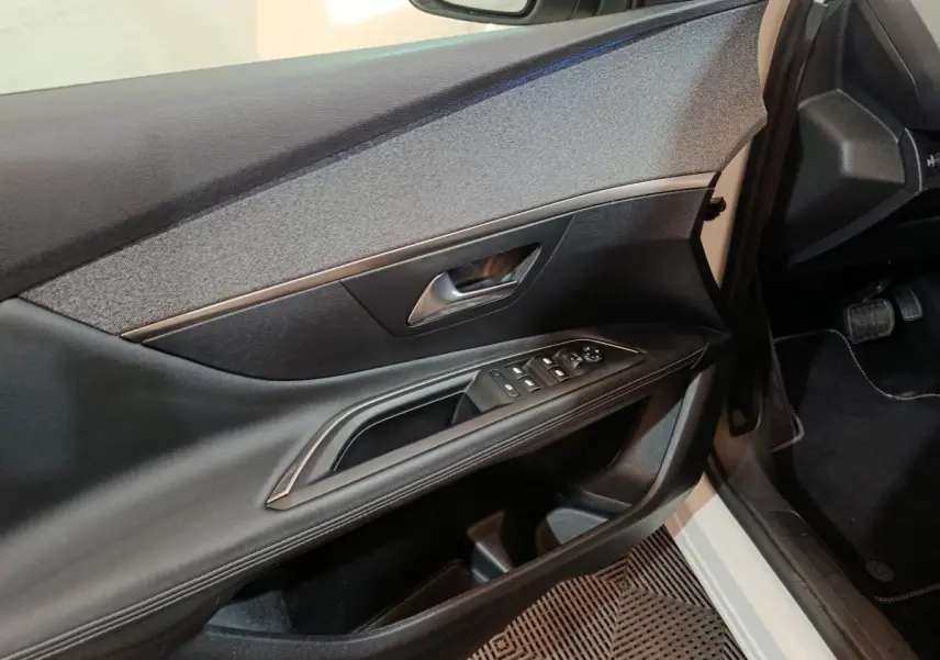 Vue intérieure côté conducteur de la porte d’un Peugeot 3008 blanc, avec commandes électriques et garniture textile grise.