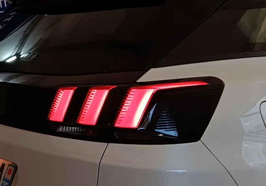 Feu arrière droit allumé d'un Peugeot 3008 blanc, vue rapprochée sur la partie arrière du véhicule.