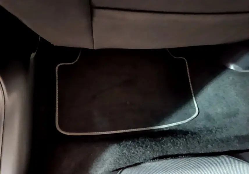 Vue rapprochée du sol côté arrière d’un SEAT Leon 2023 gris clair, montrant la moquette et tapis de sol noir.