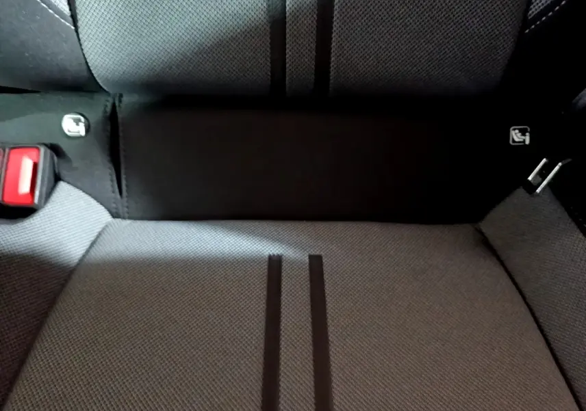 Gros plan sur la banquette arrière grise du SEAT LEON 2023 avec ceinture rouge et fixation Isofix visibles.