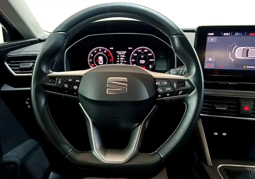 Vue rapprochée du volant en cuir noir et du tableau de bord numérique du SEAT Leon 2023, avec écran tactile latéral.