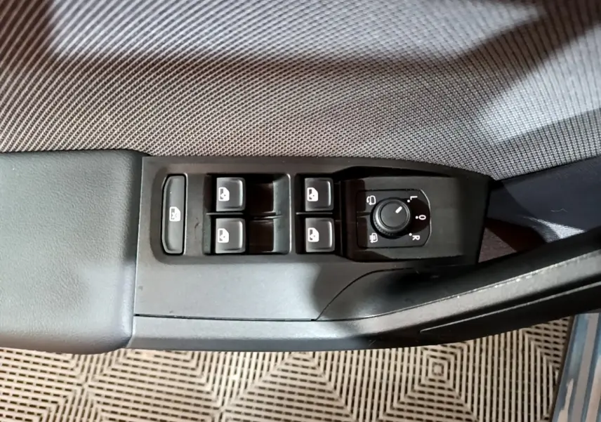 Vue rapprochée des commandes de lève-vitres et réglage des rétroviseurs sur la porte côté conducteur d'une SEAT Leon gris clair.